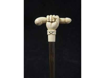 Lot 98 : Une canne à pommeau en ivoire sculpté représentant une main tenant un phallus. Fût en bois de palmier ; férule en fer et longueur de 85 cm. Estimation est de 1 800 à 2 000 € (c) Millon et associés.